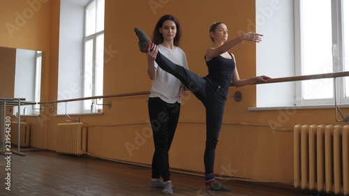 ballet teacher at dance studio help to stretch her student 
