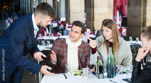 Angry customers in restaurant talking with administrator