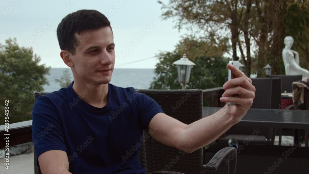 4K A handsom man makes selfie on smartphone. 4K A handsom man makes selfie on smartphone.