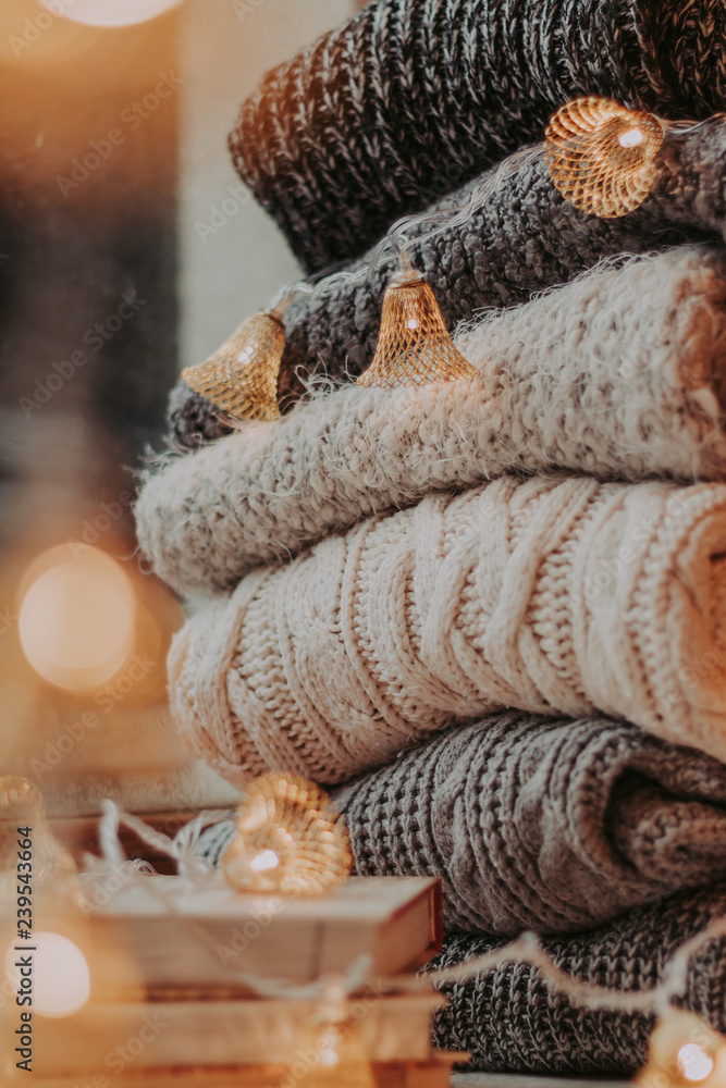 Home decor, sweaters, a stack of books and light bulbs, cozy winter interior details. Home decor, sweaters, a stack of books and light bulbs, cozy winter interior details.