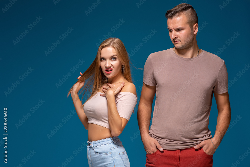 Fototapeta premium Pretty woman turns away, feels tired and annoyed with her husband who is outraged