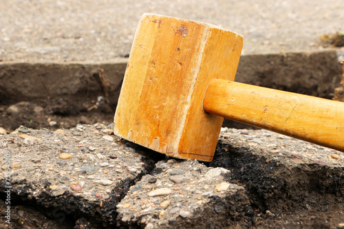 A wooden hammer breaking the asphalt. Close-up.