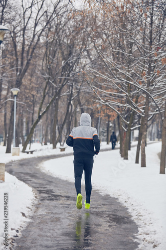 Man jogging in a cold winter snowy day outdoors. © astrosystem