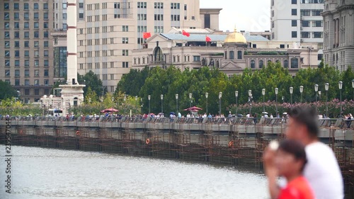 People walking on a boulvard by the river in Shanghai by day photo