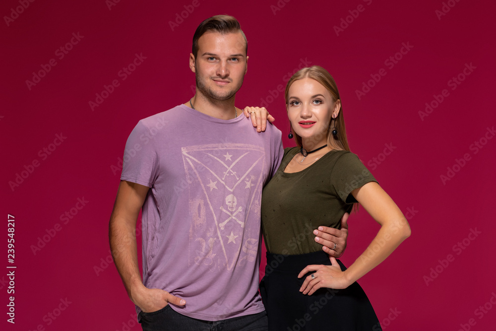 Young nice couple posing in the studio, express emotions and gestures, smiling, on a burgundy background Young nice couple posing in the studio, express emotions and gestures, smiling, on a burgundy background