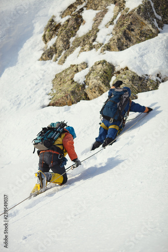 Two climbers on a snow-covered mountain slope.
