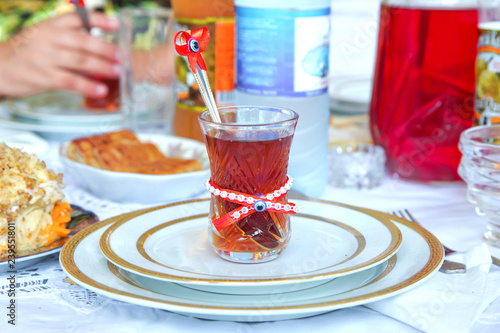 tea ceremony tea cups in engagement day. Sweet tea and pomegranate in a bowl. Spoon in the cup. On top of the glass eye beads and red tape.