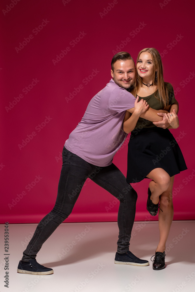 Totally in love. Full length of beautiful young couple embracing and smiling while standing against burgundy background Totally in love. Full length of beautiful young couple embracing and smiling while standing against burgundy background