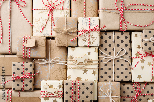 Christmas background with many decorative homemade gift boxes wrapped in brown kraft paper. Flat lay.