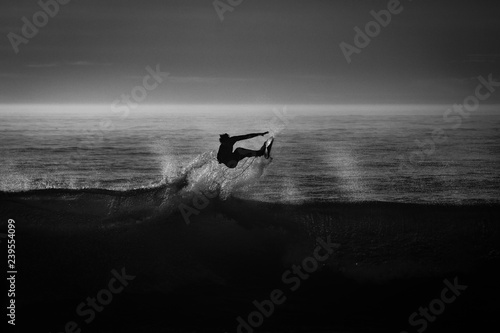 silueta de un surfista en blanco y negro y a contraluz	