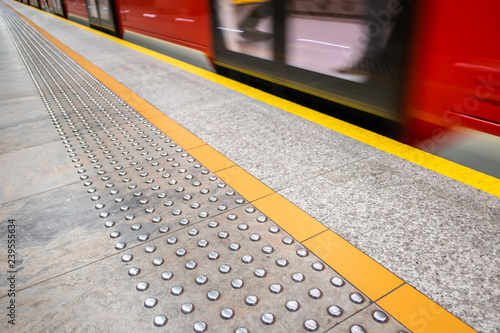 blurred red subway train in Warsaw Poland, diagonal tactile pavi