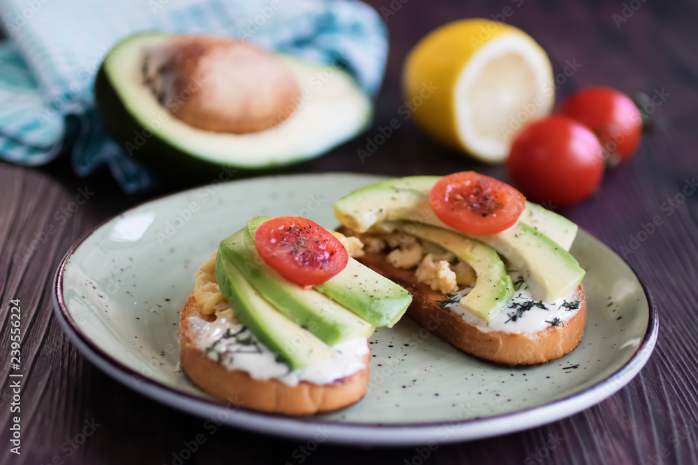 Toasts with avocado pieces, cherry tomatoes, scrambled eggs and soft cream cheese. Toasts with avocado pieces, cherry tomatoes, scrambled eggs and soft cream cheese.