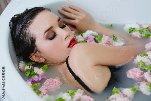 beautiful sexy sad young slim brunette woman in spa - bathroom with water and flowers