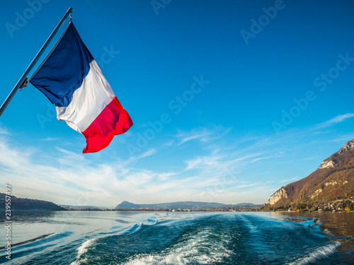 French Tricolore as seen from the stern of a boat on Lake Annecy, Europe's cleanest lake, Annecy, Haute-Savoie, France, Europe