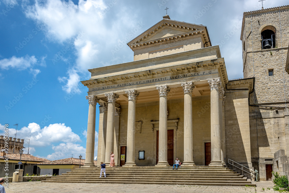 San Marino, San Marino - May 19th 2018 - Tourists and locals walking in front of a church in San Marino in a blue sky day San Marino, San Marino - May 19th 2018 - Tourists and locals walking in front of a church in San Marino in a blue sky day