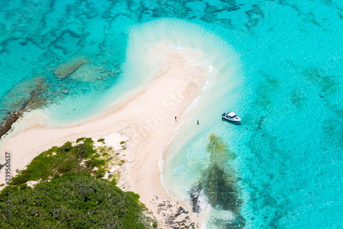 Tourists, divers, snorkelers, jet boat, an idyllic empty sandy beach of remote island, azure turquoise blue lagoon, West Coast barrier reef, aerial view. New Caledonia, Melanesia, South Pacific Ocean photo