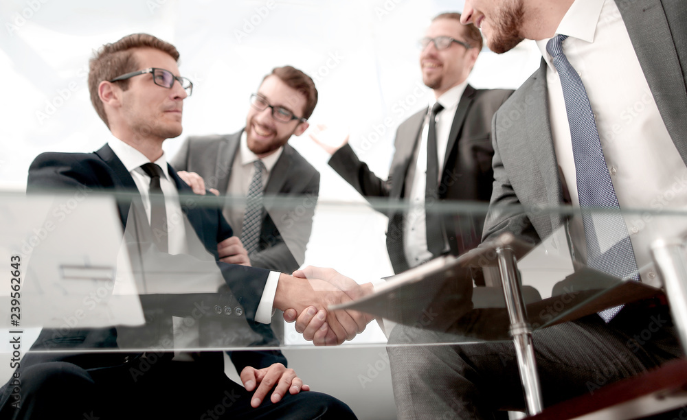 bottom view.business partners shaking hands sitting at the Desk bottom view.business partners shaking hands sitting at the Desk