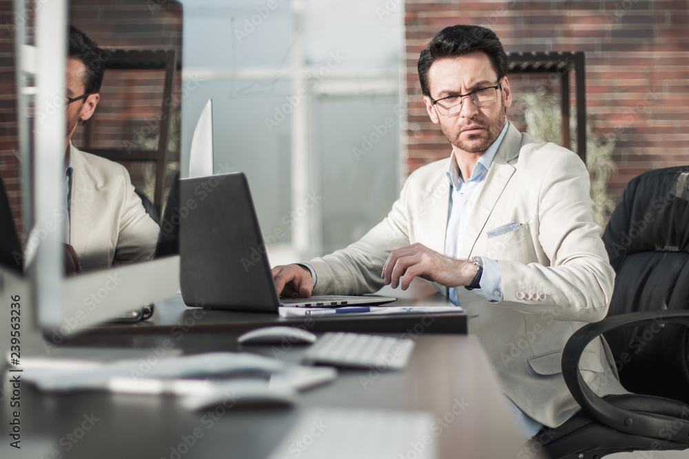 behind the glass.a serious businessman using a laptop