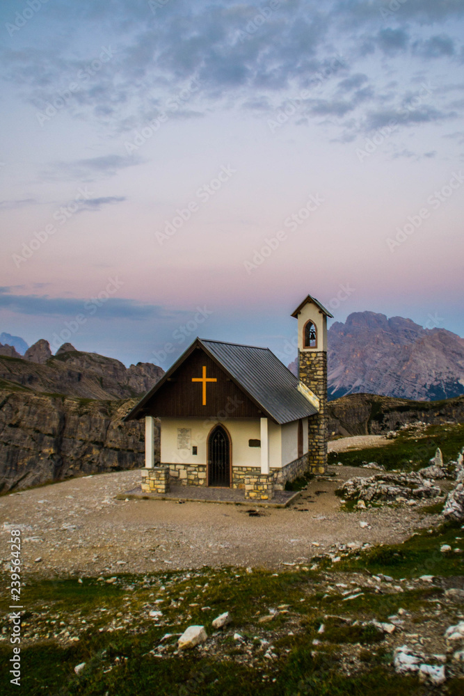 Breathtaking summer scenic landscape view of iconic Cappella degli Alpini chapel while sunrise in famous Tre Cime di Lavaredo mountains in the Dolomites mountain range, South Tirol Alps, Italy, Europe