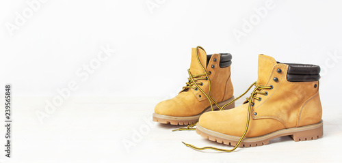 Yellow men's work boots from natural nubuck leather on wooden white background. Trendy casual shoes, youth style. Concept of advertising autumn winter shoes, sale, shop.