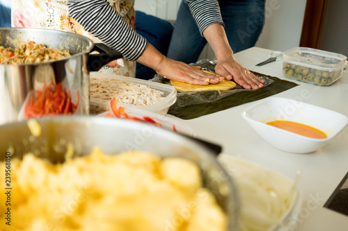 hands of young woman making venezuelan christmas dish hallacas with all ingredients on table photo