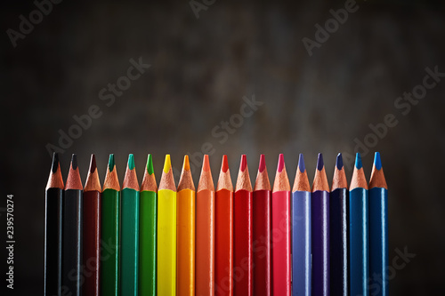 Colorful pencils in row on a dark background close up