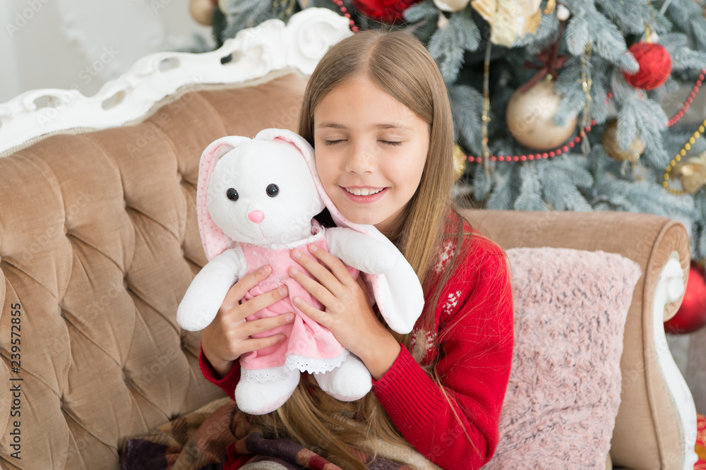 The cutest little toy ever. Small girl hug rabbit toy. Best Christmas toy. Little girl with cute bunny at Christmas tree. Little child play with soft toy. Small child happy smiling with present The cutest little toy ever. Small girl hug rabbit toy. Best Christmas toy. Little girl with cute bunny at Christmas tree. Little child play with soft toy. Small child happy smiling with present