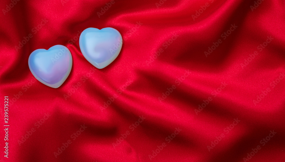 Fototapeta premium Valentines day. Top view of light blue glass hearts, red silk background.