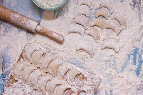 Dumplings with rolling pin on table sprinkled with flour