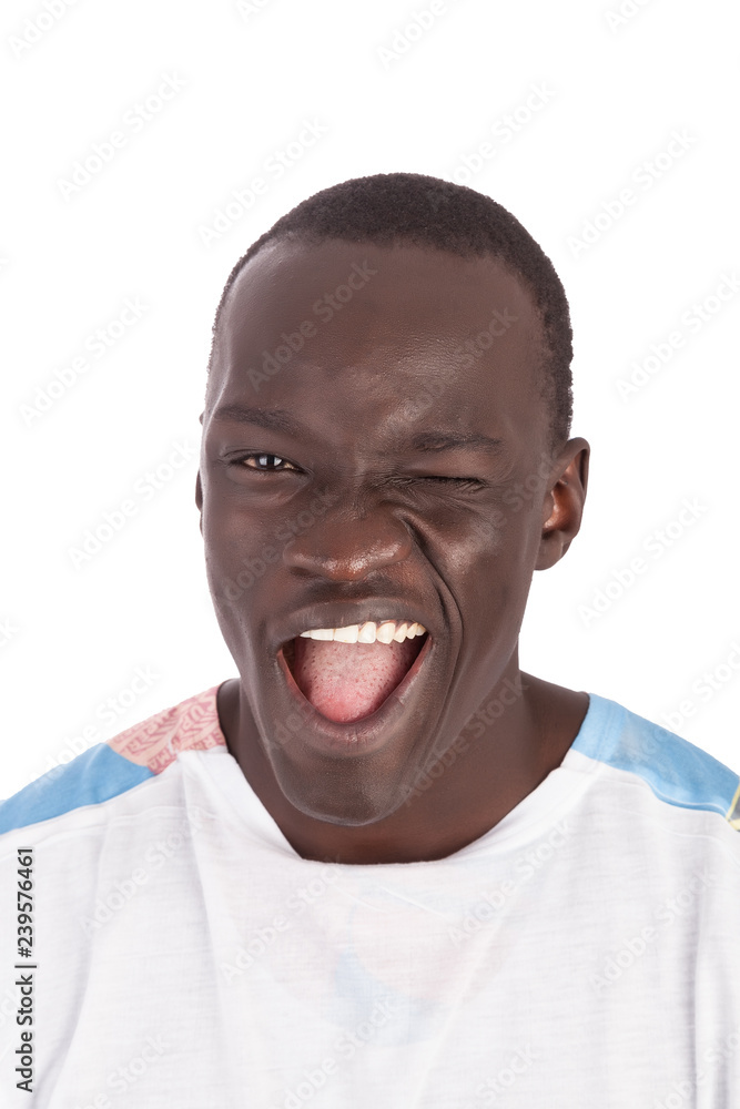Young handsome Sudanese man face to camera in white tshirt winking, smiling with white teeth and pink tongue showing, straight face mouth open in portrait format with copy space isolated on white. Young handsome Sudanese man face to camera in white tshirt winking, smiling with white teeth and pink tongue showing, straight face mouth open in portrait format with copy space isolated on white.