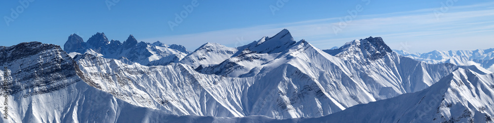Large panorama of snowy mountains and blue sky