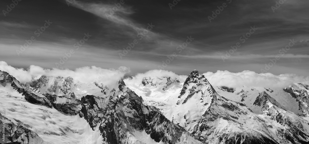 Black and white panorama of snowy winter mountain and sky with clouds
