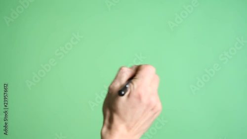 Male Hand Writing On Green Screen. Hand writing with a marker pen on a green screen background.