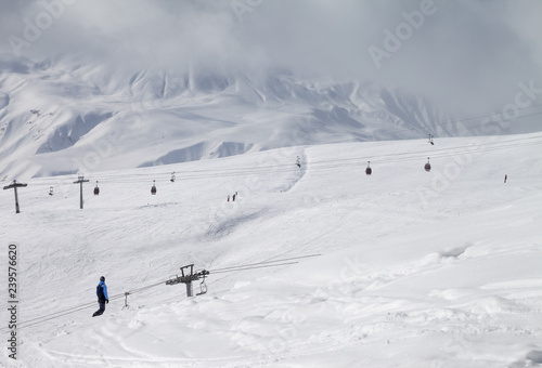 Snowboarder descend on snowy ski slope and high mountains in dark cloud