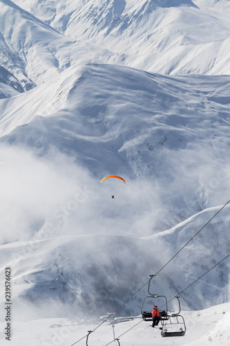 Chair-lift and paraplane in fog on ski resort