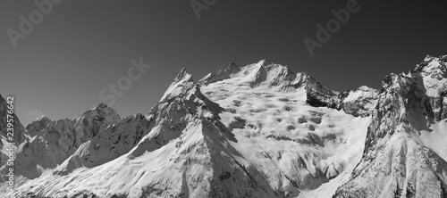Panorama of snowy covered mountain peaks and clear sky at sun winter day