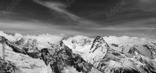 Black and white panorama of snowy winter mountain and sky with clouds