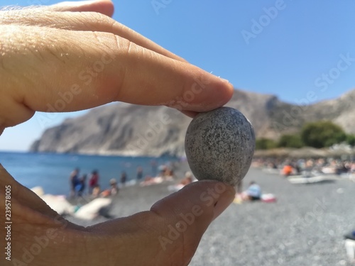 Una pietra tra le mani in equilibrio sulla spiaggia di Camari, Santorini - Grecia photo