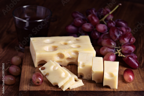 Wine grape and portions of Spanish cheese on wood with selective light