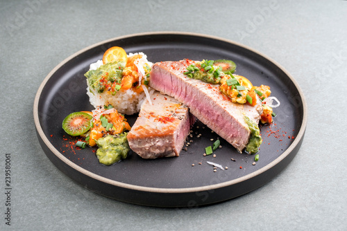 Fotografia Traditional exotically tuna fish fillet with mango salsa and rice as closeup on