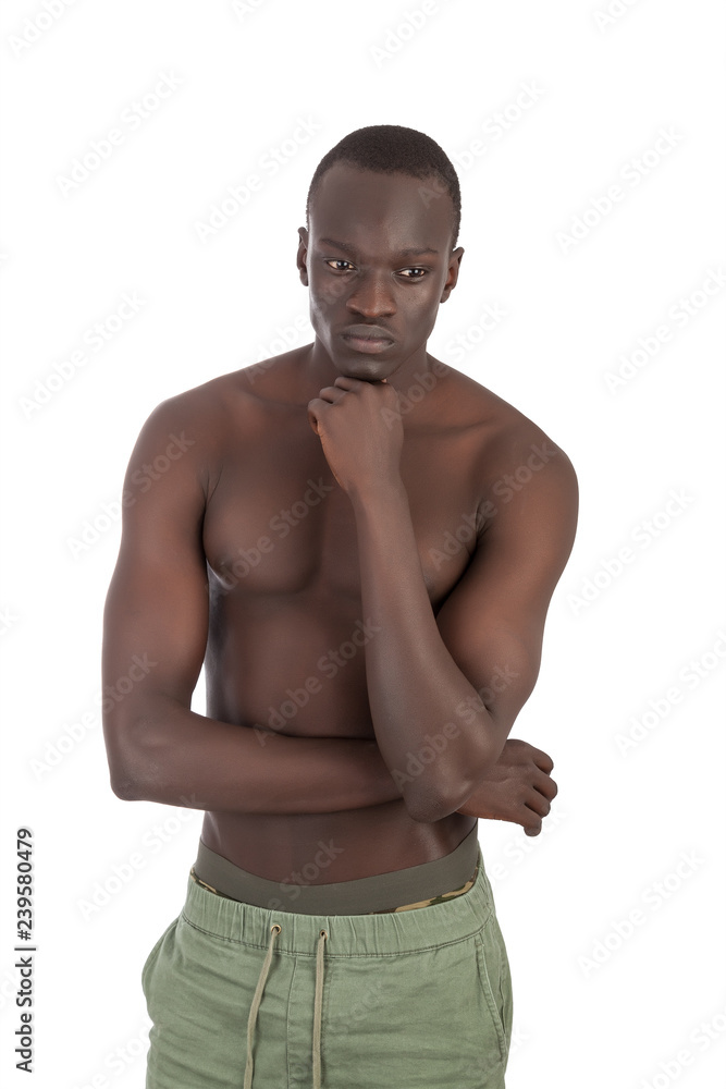 Young buff Sudanese man naked torso in khaki trousers looking to away  avoiding eye contact, arms