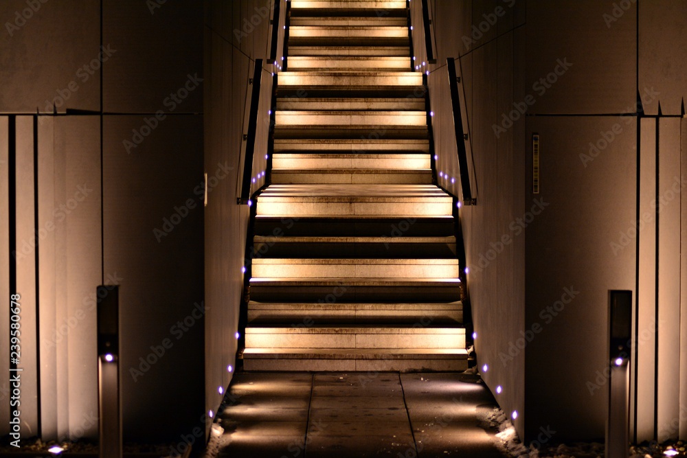 Fototapeta premium illuminated apartment building staircase exhaling up to entrance in night city