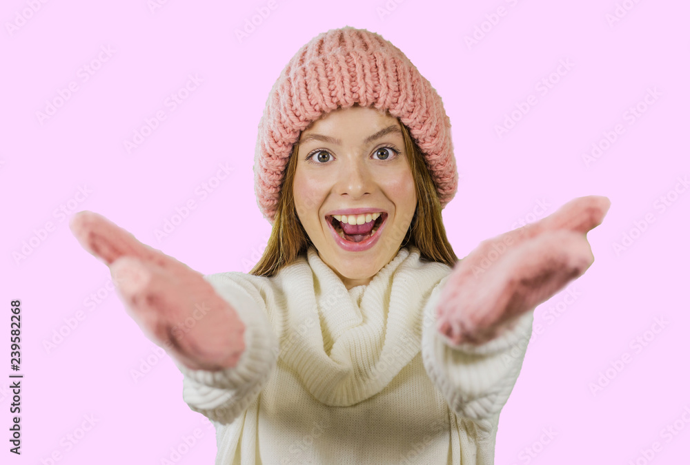 Girl in knitted hat and gloves is smiling and holding out her hands in greeting on an isolated background Girl in knitted hat and gloves is smiling and holding out her hands in greeting on an isolated background