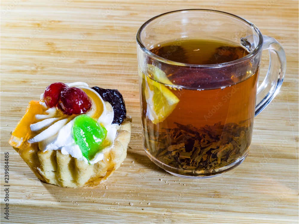 Black tea in a glass tea Cup, Shortbread, lemon, waffles, cakes baskets Black tea in a glass tea Cup, Shortbread, lemon, waffles, cakes baskets