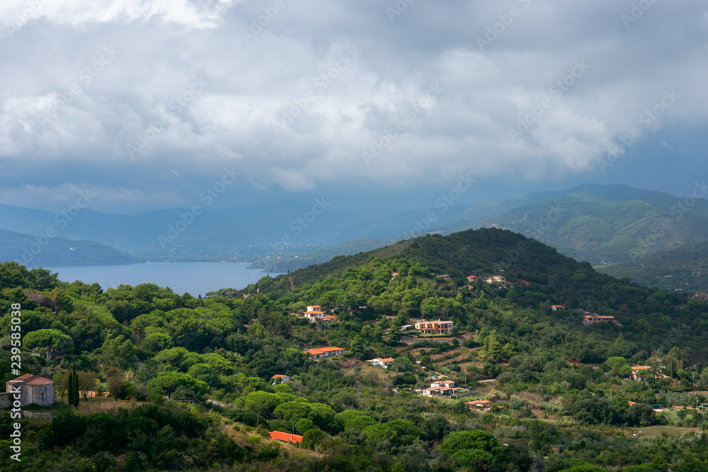 Beautiful view of the hills and the sea lagoon under a cloudy sky on Elba Island in Tuscany, Italy