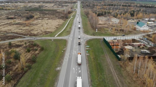 The camera takes off over the road, escorting a string of trucks. photo