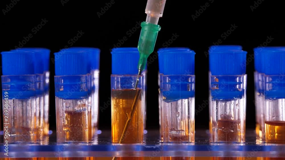 Test tubes and needle with orange liquid in medical lab Test tubes and needle with orange liquid in medical lab