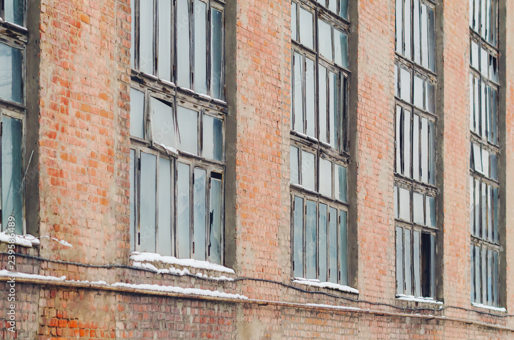 The facade of an old abandoned factory with broken windows The facade of an old abandoned factory with broken windows