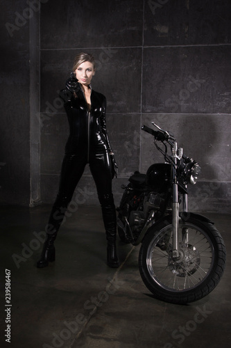 Biker girl in a latex suit with gun in hand