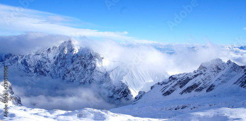alpen berge mit sky und snowboard urlaubern am rand der schlucht mit toller aussicht auf berge himmel felsen und wolken © Maxim